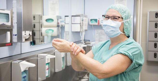 Ulrike Fertig mit Mundschutz reinigt ihre Hände