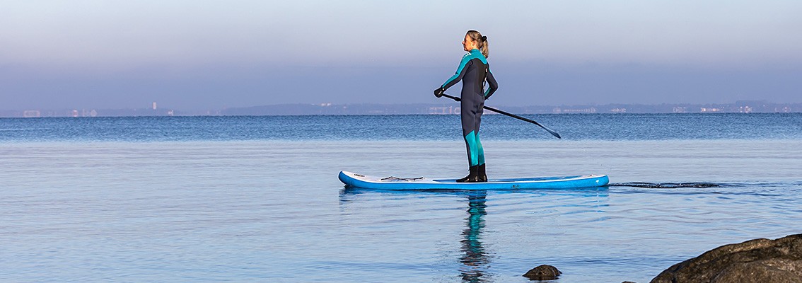 Eine Frau auf dem Wasser und betreibt den Wassersport 'Stand Up Paddeln'